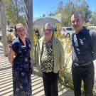 Photo of three people standing outside on a sunny day. 